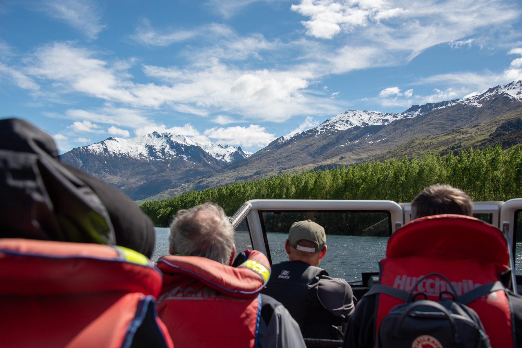 Jet boat guests on the Matukituki River with snow-covered peaks and beech forest on the valley sides